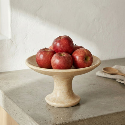 CRUSOË black marble pedestal cake stand with red apples on a concrete countertop.