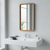 CRUSOË Lyndi rectangular mirror with rounded teak wood frame, mounted above a white sink.
